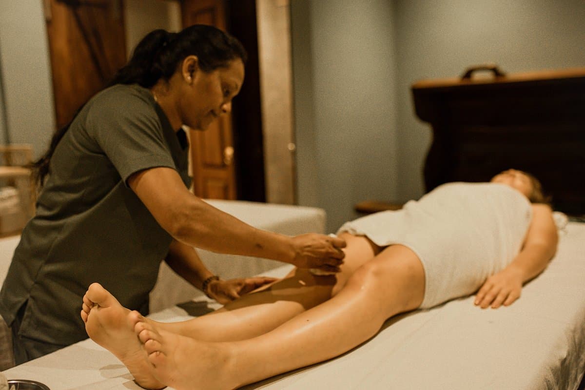 A therapist working along a guest's lower legs and feet on the treatment table